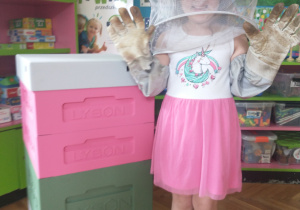Dziewczynka w białej bluzce w stroju pszczelarza